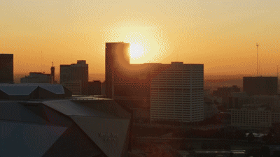 Time-lapse of the sun rising over a turnkey city skyline, with sunlight illuminating tall buildings and casting long shadows.