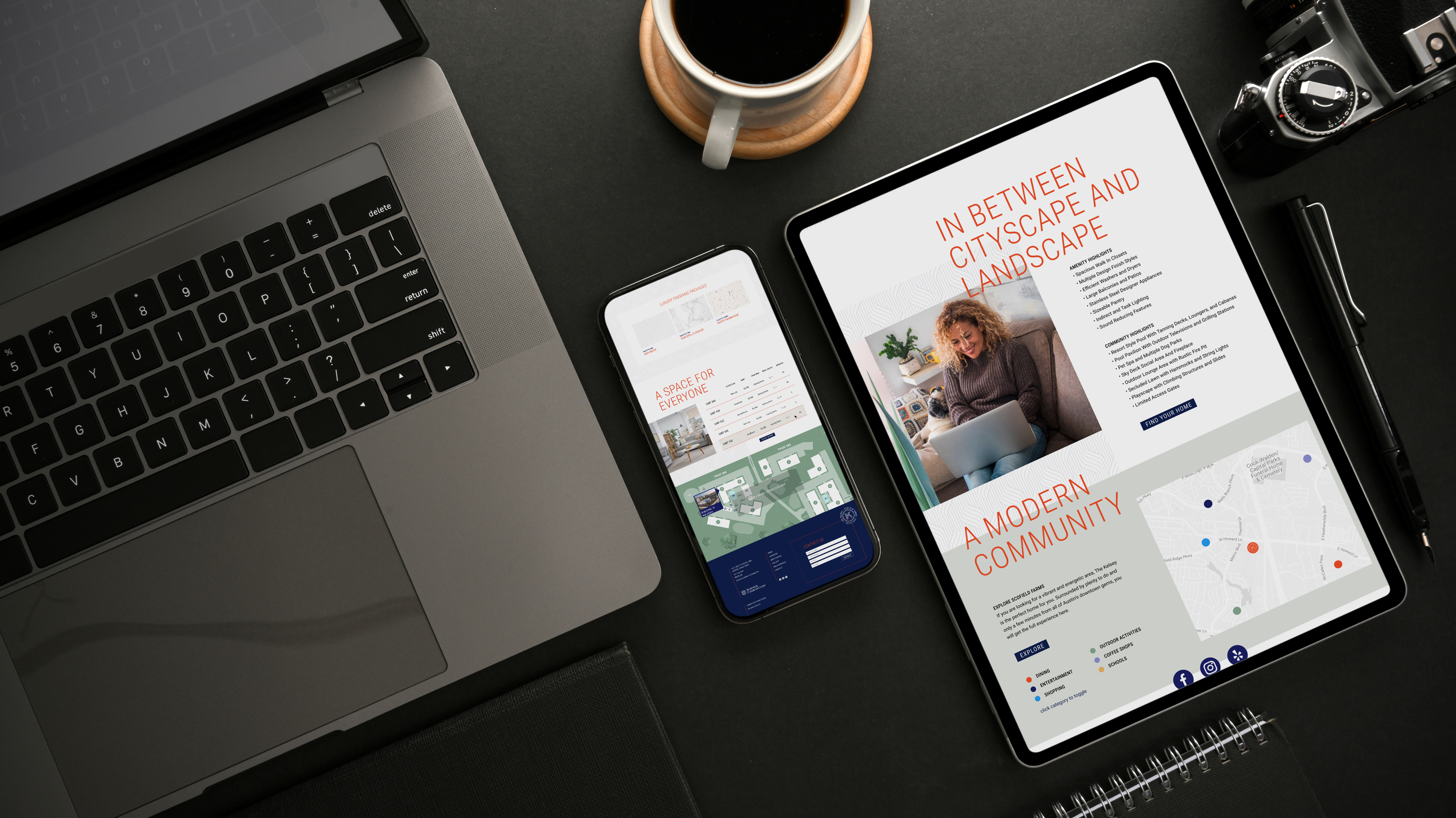 A laptop, smartphone, tablet displaying digital content, camera, pen, and coffee cup are arranged on a dark turnkey desktop.